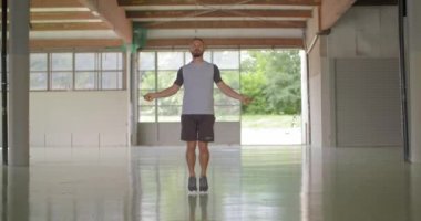 Fitness spor egzersiz sırasında atlama ipi ile atlama egzersiz yaparak genç yetişkin adam. Grunge endüstriyel kentsel training.4k ağır çekim video