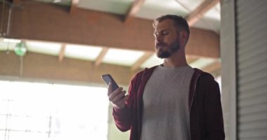 Kapüşonlu sweatshirt fitness spor egzersiz sırasında smartphone kullanarak genç yetişkin adam. Grunge endüstriyel kentsel training.4k ağır çekim video