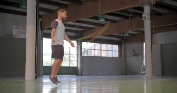 Молодий дорослий чоловік пропускає вправи зі стрибковою мотузкою під час тренувань з фітнесу. — стокове відео