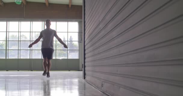 Jonge volwassen man doen overslaan oefening met springtouw tijdens sport fitnesstraining. Grunge industriële stedelijke training.4k slowmotion video — Stockvideo