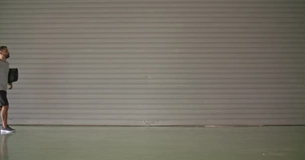 ローリングと歩く若い成人男性フィットネス スポーツ トレーニング前にスマート フォンを使用してマット。グランジ産業都市 training.4k スロー モーション ビデオ — ストック動画