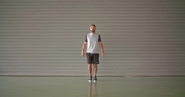 Νεαρός άνδρας ενηλίκων προθέρμανση διατάσεις κατά τη διάρκεια της προπόνηση fitness sport. Πλαϊνή όψη. Grunge βιομηχανική αστική training.4k βίντεο αργής κίνησης — Αρχείο Βίντεο