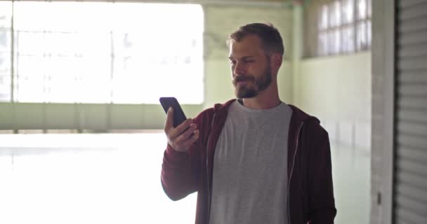 Hombre adulto joven con sudadera con capucha usando teléfono inteligente durante el entrenamiento deportivo de fitness. Grunge entrenamiento urbano industrial. — Vídeos de Stock