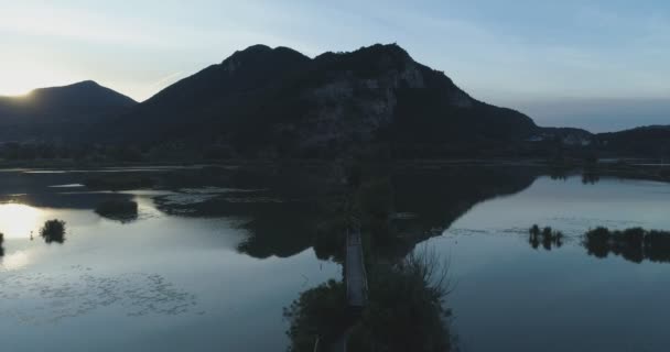 Avançando para o lago nascer do sol ao longo do caminho da ponte de madeira no verão.Europa Itália paisagem natureza verde ao ar livre estabelecer.4k voo drone selvagem estabelecendo tiro — Vídeo de Stock