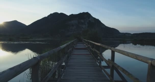 POV pohledu chůze po lesní cestě most na jezeře při východu slunce v létě. Evropa zelené přírody stvol divoké establisher.4k založení shot — Stock video