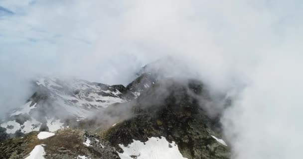 Vorwärts Luftaufnahme über bewölkt felsigen schneebedeckten Berg bei sonnigem Tag mit Wolken. Italienischen Alpen Berge im Sommer mit wildem, windigem Wetter Outdoor-Natur-Betriebe. 4k Drohnenflug Einrichtungsschuss — Stockvideo
