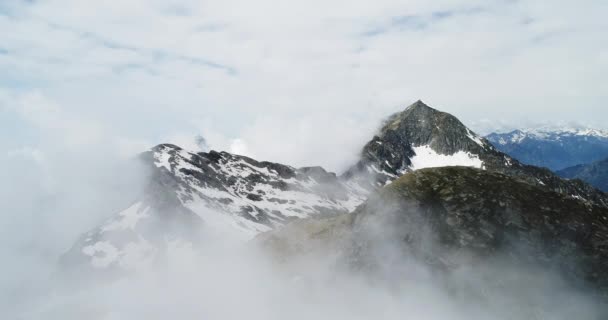 Luchtfoto bovenaanzicht toekomen over bewolkt rotsachtige besneeuwde berg in zonnige dag met wolken. Italiaanse bergen van de Alpen in de zomer met wild winderig weer buiten natuur establisher.4k drone vlucht tot oprichting van schot — Stockvideo