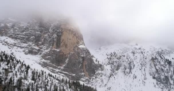 Achterwaartse antenne met besneeuwde berg en bos bos in Sella doorgeven kantelen naar beneden. Bewolkt slechte bewolkte mistig weer. Winter Dolomieten Italiaanse Alpen bergen buiten natuur establisher.4k drone vlucht — Stockvideo