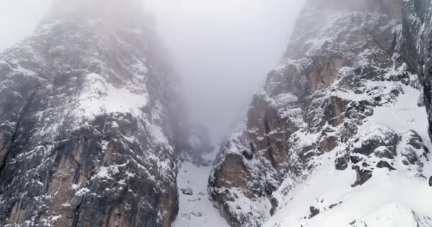 Karlı kayalık dağ aşağı eğerek üzerinden geriye dönük anteni. Bulutlu kötü sisli hava bulutlu. Kış Dolomites İtalyan Alpleri dağlar açık doğa establisher.4k drone uçuş — Stok video