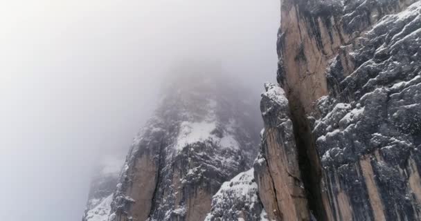 Aérea hacia atrás desde la montaña rocosa nevada inclinándose hacia abajo.Nublado mal nublado niebla clima.Invierno Dolomitas Alpes italianos montañas naturaleza al aire libre establecier.4k vuelo drone — Vídeos de Stock
