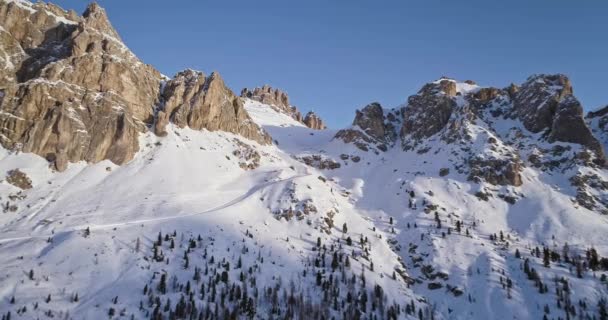 ファルザレゴ峠で雪に覆われた岩山に前方の空中。夕日や日の出、澄んだ空、晴れた。冬ドロミテ イタリア アルプス山脈屋外の自然 establisher.4k 無人飛行 — ストック動画
