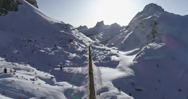 Avión delantero siguiendo los coches en la carretera en el valle nevado en el paso de Valparola. Soleado atardecer o amanecer, cielo despejado. Dolomitas de invierno Alpes italianos montañas naturaleza al aire libre Establecimiento. — Vídeo de stock