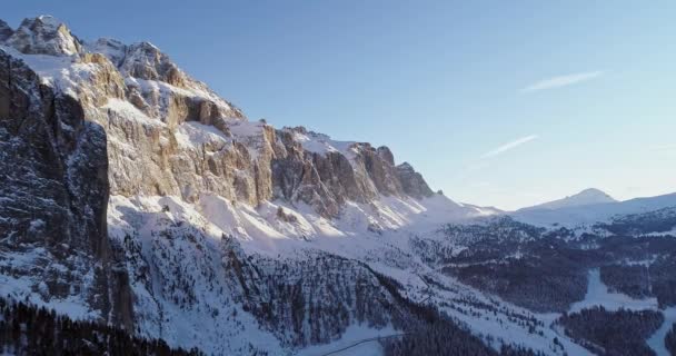 Bajando aérea a lo largo de nevado alpino escarpado valle rocoso acantilado con bosques bosque.Unset o amanecer, cielo claro.Invierno Dolomitas Alpes italianos montañas naturaleza al aire libre establishment. — Vídeo de stock