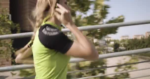 Mujer rubia joven en el entrenamiento de funcionamiento de la ropa de fitness en la pasarela aérea.Lado siguiente view.Summer día soleado.Ciudad verde industrial.Corredor urbano ejercicio de actividad cardio saludable.4k cámara lenta 60p video — Vídeos de Stock