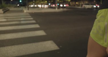 Kadın fitness aşınmaya zebra kapısı üzerinde çalışan. Arkadan aşağıdaki görünüm. Yaz akşam veya gece. Endüstriyel yeşil şehir. Kentsel runner kardiyo sağlıklı faaliyet workout.4k ağır çekim 60p video.
