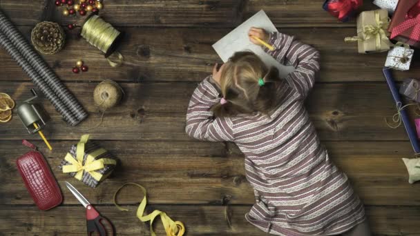 Napowietrznych dziecko dziewczynka pisanie listu dar santa claus na vintage drewniany stół z narzędziami grawerować. Pionowy widok z góry. Karty socjalnej na Boże Narodzenie lub zimowe wakacje season.4k wideo — Wideo stockowe