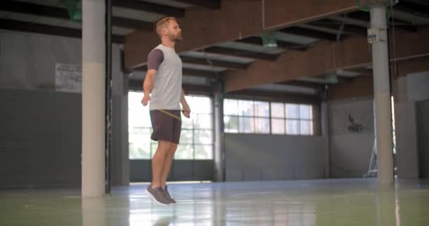 Νεαρός άνδρας ενηλίκων κάνει παρακάμπτοντας άσκηση με το σχοινάκι κατά τη διάρκεια της προπόνηση fitness sport. Grunge βιομηχανική αστική training.4k βίντεο αργής κίνησης — Αρχείο Βίντεο