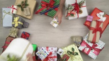 Bazı hediyeler koyarak genel gider elleriyle. Metin veya logo kopya alanı. Ahşap masa Noel hediye kutuları tam dikey üstten görünüm. Xmas tatil sezonu sosyal kartı background.4k video