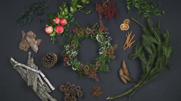 Main de la personne aérienne prenant guirlande sur l'espace de copie de texte.Vue verticale du dessus de la table sombre avec des feuilles naturelles, des cônes de pin, de l'écorce, de la grenade. — Video