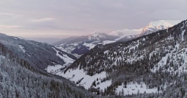 Backward aerial to snowy valley with woods forest at Sella pass.Sunset or sunrise, cloudy sky.Winter Dolomites Italian Alps mountains outdoor nature establishment isher.4k drone flight — стоковое видео