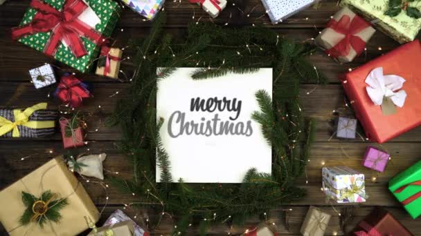 Накладні веселі різдвяні та щасливі новорічні прикраси на темно-сірій рамці з сосновими шишками, подарунками, червоними та золотими стрічками, блимаючими вогнями. Вертикальний вид зверху. Різдвяний святковий сезон соціальної картки.4k відео — стокове відео