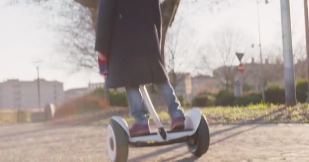 快乐微笑的女儿女儿女孩戴安全帽肖像骑赛格威在城市公园 未来的科技 走在城市户外 温暖的日落背光 慢动作视频 — 图库视频影像
