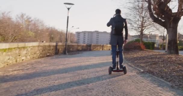 Business man riding segway in city commuting to work or home while calling using smartphone.Modern future transport technology.Sidewalk urban outdoor.Warm sunset backlight.4k slow motion 60p video — Stock Video