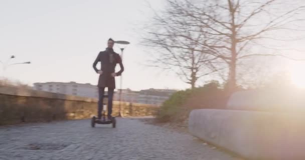 Homme d'affaires circonscription segway dans la ville de se rendre au travail ou à la maison tout en appelant en utilisant smartphone.Modern future technologie de transport .Sidewalk extérieur urbain.Rétroéclairage chaud coucher de soleil. — Video