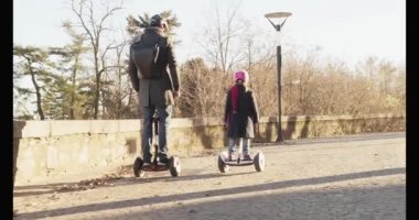Kız kız çocuk babası şehirde Segway sürme. Modern gelecekteki ulaşım teknolojisi. Active Family.Park kaldırım kentsel açık. Sıcak gün batımı soğuk hava backlight.4k ağır çekim 60p video