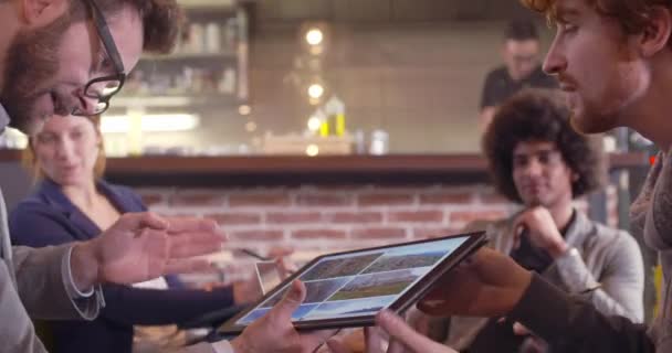 Коллеги и клиенты обсуждают стратегию с ноутбуком и таблицей. Группа мультиэтнических людей, имеющих неформальную деловую команду, встречается в ресторанном салоне. — стоковое видео