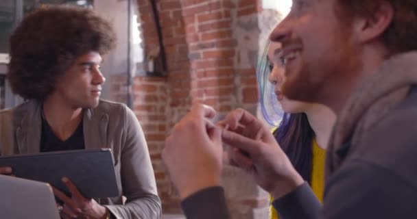 Collega's en klanten praten strategie met laptop en tablet. Groep van multi-etnische mensen die informele zakelijke teamvergadering in restaurant lounge. Teamwork, corporate, diversiteit en sociale concepten — Stockvideo