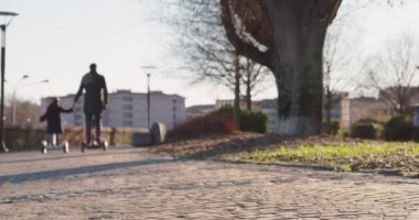 Kız kız çocuk babası şehirde Segway sürme. Modern gelecekteki ulaşım teknolojisi. Active Family.Park kaldırım kentsel açık. Sıcak gün batımı soğuk hava backlight.4k ağır çekim 60p video