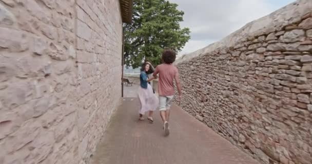Pareja romántica caminando visitando la feliz ciudad rural de Assi.Back follow.Friends viaje italiano en Umbria.4k cámara lenta — Vídeos de Stock