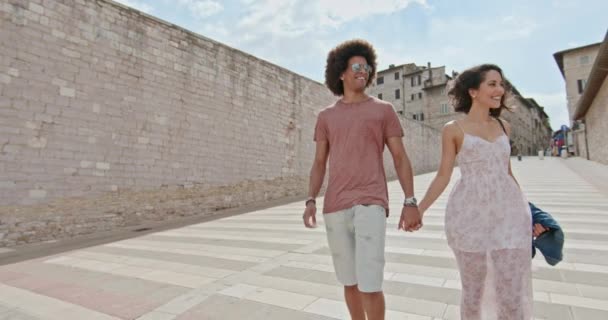 Pareja romántica caminando sintiéndose libre y feliz a la plaza principal en la ciudad rural de Assi.Medium shot.Friends viaje italiano en Umbria.4k cámara lenta — Vídeos de Stock