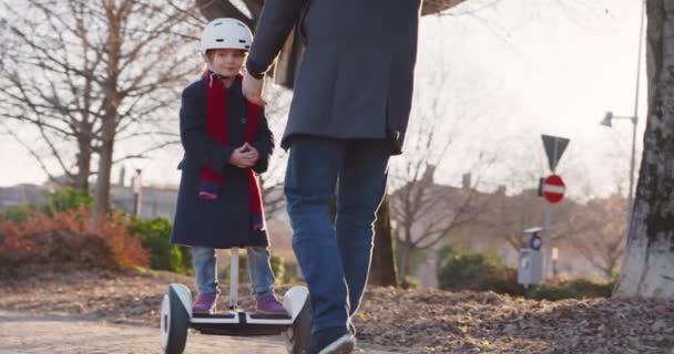 女儿的女孩学习赛格威骑与爸爸在城市教学。现代未来运输技术。活跃的安全家庭。走在城市户外。温暖的日落冷光. 4k 慢动作60p 视频 — 图库视频影像