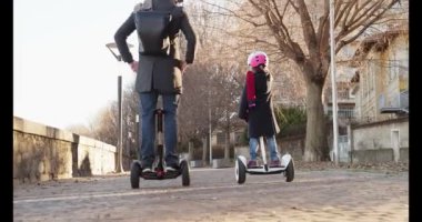 Kız kız çocuk babası şehirde Segway sürme. Modern gelecekteki ulaşım teknolojisi. Active Family.Park kaldırım kentsel açık. Sıcak gün batımı soğuk hava backlight.4k ağır çekim 60p video