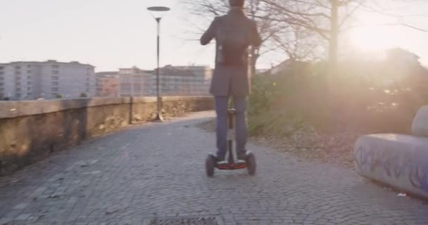 Biznes człowiek jazda segway w mieście dojazdy do domu podczas nawiązywania połączenia przy użyciu smartfona lub pracy. Nowoczesny transport przyszłych technologii. Chodnik miejski odkryty. Ciepły backlight.4k zachód zwolnionym tempie wideo 60p — Wideo stockowe