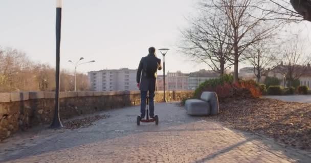 Επιχείρηση άνθρωπος ιππασία segway για μετακινήσεις στην πόλη για δουλειά ή σπίτι ενώ κλήση χρησιμοποιώντας το smartphone. Σύγχρονη μελλοντικές μεταφορές τεχνολογίας. Πεζοδρόμιο αστική εξωτερική. Ζεστό ηλιοβασίλεμα backlight.4k αργή κίνηση 60p βίντεο — Αρχείο Βίντεο