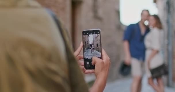 Femme photo de tir avec appareil smartphone à des amis heureux touristes dans la petite rue visiter la ville rurale de Spello.Retour follow.Friends voyage italien en Ombrie 4k slow motion — Video