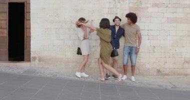 Dört mutlu turist arkadaşlar poz, gülümseyerek ve Umbria.4k yavaş hareket Spello.Friends kırsal kasabasında bir tuğla duvar yakınında eğlenmek