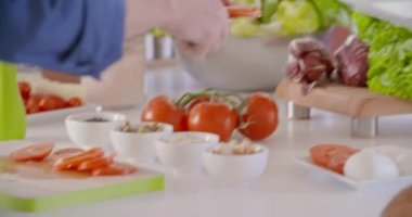 Eller yemeğin üzerine domates koyarak. Genç çift yemek ve öğle veya akşam yemeği için ev açık alan mutfakta yemek hazırlanıyor. Sağlıklı beslenme sebzeleri, salata. Modern aşk ilişkisi, yardım