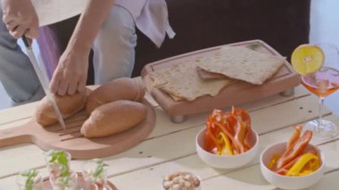 Bıçaklı ekmek kesen adam meze hazırlıyor. Mutlu insanlar grup modern ev partisi akşam yemeği veya öğle yemeği tadını çıkarın. El videosu