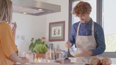 adam çırpma veya yumurta karıştırma yenerek. Genç insanlar çift yemek ve yemek hazırlama, öğle veya akşam yemeği için spagetti makarna carbonara yemek modern ev açık alan mutfakta. Modern ilişki, yardım