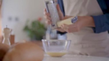 rende ile man el rendeleme parmesan peyniri detay. Genç insanlar çift yemek ve yemek hazırlama, öğle veya akşam yemeği için spagetti makarna carbonara yemek modern ev açık alan mutfakta.