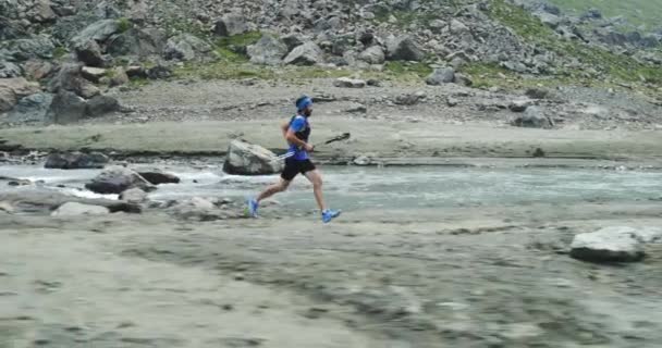 Hombre corriendo cerca de la montaña arroyo river.Trail corredor correr a la parte superior del pico de entrenamiento en la escalada rocosa.Naturaleza verde salvaje al aire libre en el mal tiempo nublado niebla. Actividad, deporte, esfuerzo, desafío, conceptos de fuerza de voluntad — Vídeos de Stock