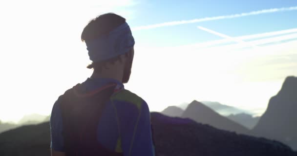地平線を見て山頂の目標に達して走るトレイルランナーの男。肖像画のショット。日の出や日没のバックライトで屋外の野生の自然。トレーニング活動,スポーツ,努力,挑戦,意志力の概念 — ストック動画