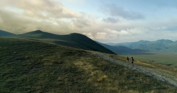 Aerial view flying above two people couple hiking or nordic walking outdoor on a trail path near Castelluccio di Norcia at sunset or sunrise.Approaching forward.Friends italian trip in Umbria.4k drone — Stock Video
