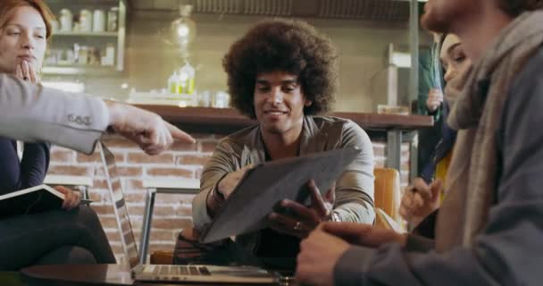 Homem conversando com colegas e clientes com laptop e tablet.Grupo de pessoas multiétnicas tendo reunião de equipe de negócios informal no salão de restauração.Trabalho em equipe, corporativo, diversidade e conceitos sociais — Vídeo de Stock