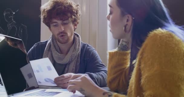 Dos jóvenes que trabajan juntos con el ordenador portátil en el restaurante o coworking.Startup negocios jobs.Man y la mujer de trabajo en equipo hablando de plan de negocios, estrategia . — Vídeos de Stock