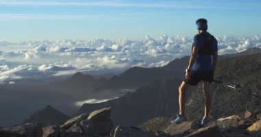 Dağ tepe hedefe ufuk görünümü görünümlü ulaşan çalışan trail koşucu adam. Geniş atış. Gün doğumu veya gün batımında açık havada vahşi doğa arkadan aydınlatmalı. Eğitim aktivitesi, spor, çaba, meydan okuma, irade kavramları